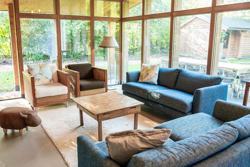 Gemütliches Wohnzimmer mit bequemer Couch, Holztisch und Pflanze.