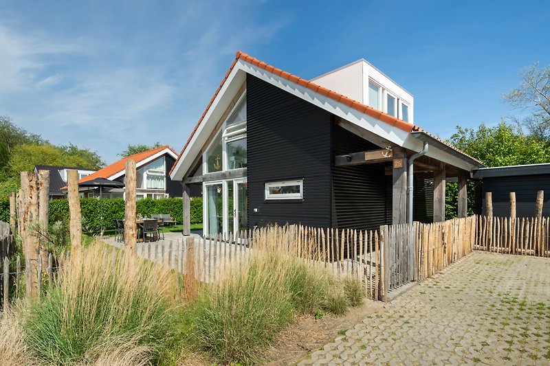 Ländliches Anwesen mit Holzfassade, grünem Garten und blühenden Pflanzen.