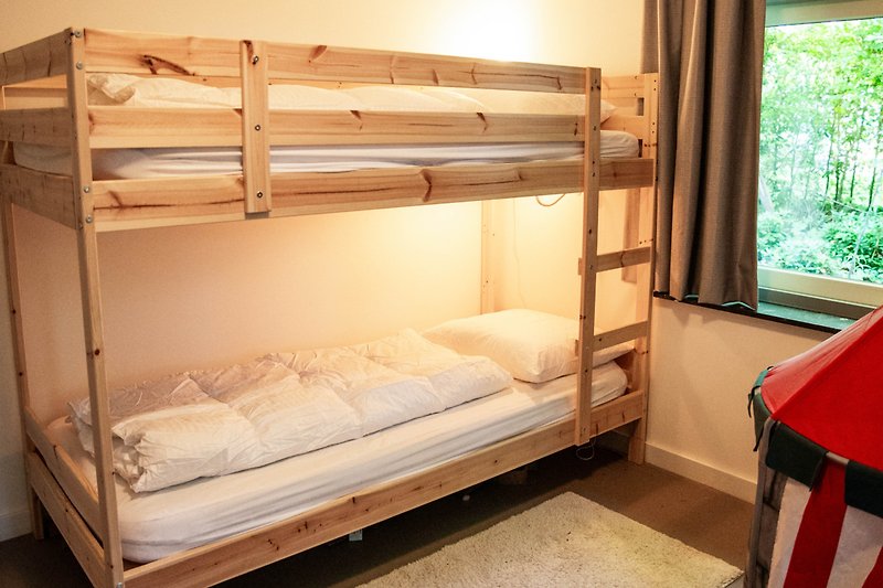 Gemütliches Schlafzimmer mit Etagenbett, Holzmöbeln und gemütlichem Bett.
