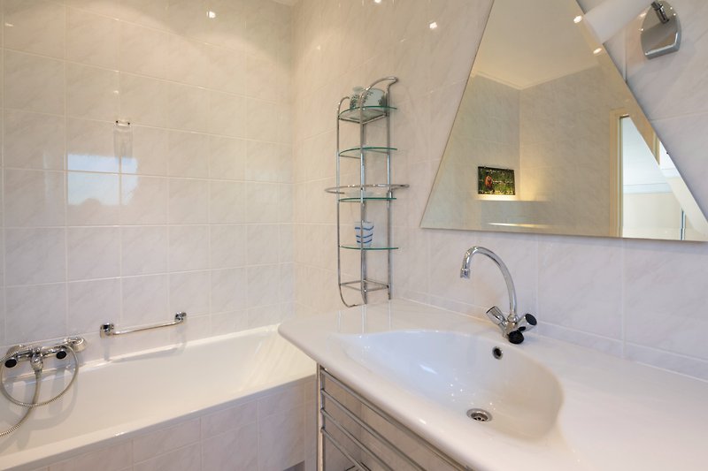 Een stijlvolle badkamer met een spiegel, bad en wastafel.