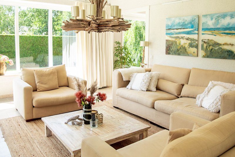 Gemütliches Wohnzimmer mit bequemer Couch, Holzmöbeln und grünen Pflanzen.