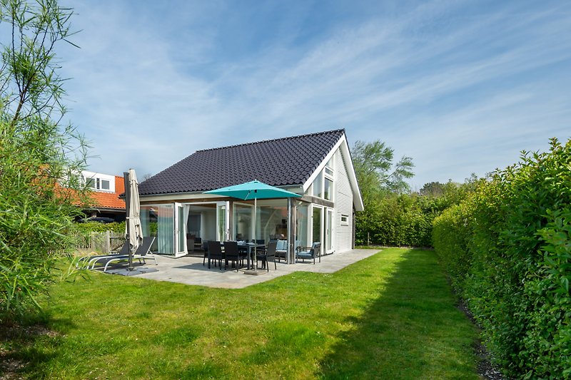 Charmantes Landhaus mit Veranda, Garten und grüner Landschaft.