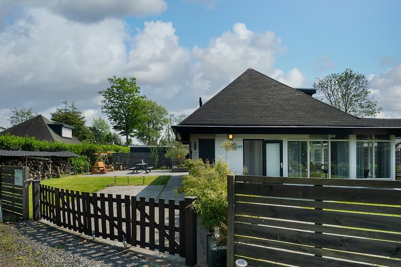 Charmantes Landhaus mit Garten, Zaun und malerischer Landschaft.