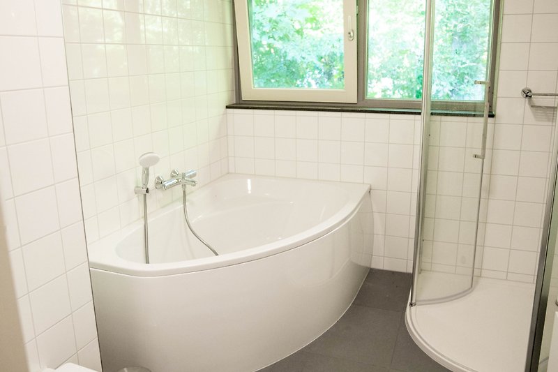 Modernes Badezimmer mit Badewanne, Fenster und stilvoller Einrichtung.