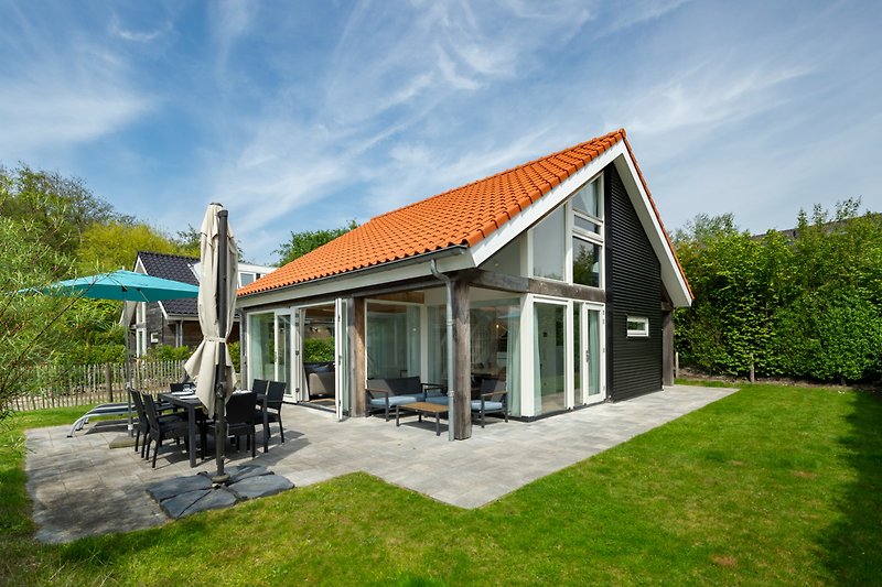 Charmantes Landhaus mit Garten, Veranda und üppiger Landschaft.