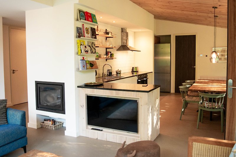 Gemütliches Wohnzimmer mit bequemer Couch, Holztisch und Fernseher.