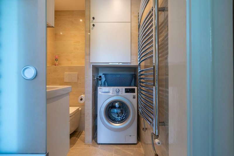 Moderne Waschküche mit blauen Geräten und Holzdekor.