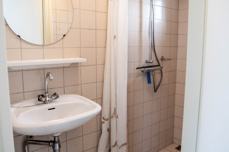 Schönes Badezimmer mit lila Waschbecken, Spiegel und Dusche.