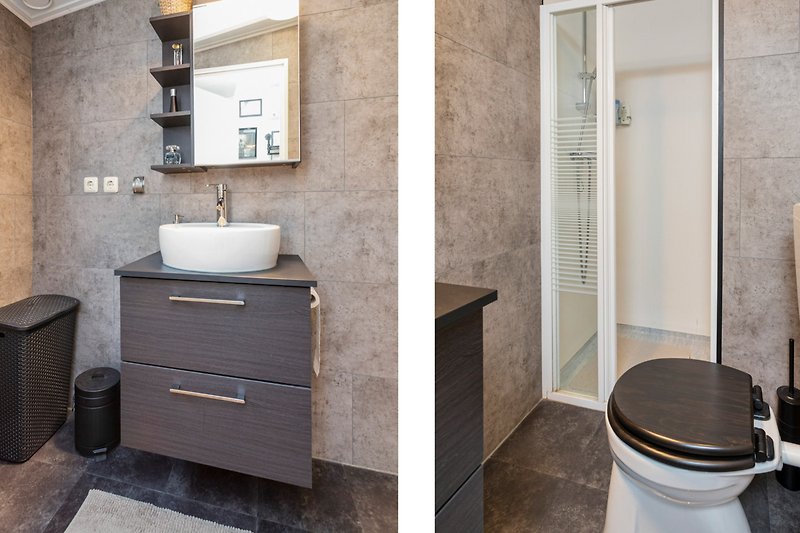 Badezimmer mit Holzschrank, Waschbecken, Spiegel und Armatur.