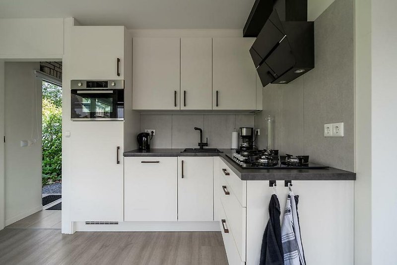 Moderne Küche mit Holz- und Glasakzenten, Kochfeld und Schränken.