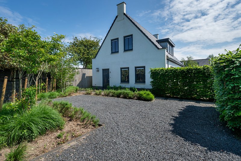 Charmantes Haus mit Garten, Bäumen und gepflegtem Rasen.