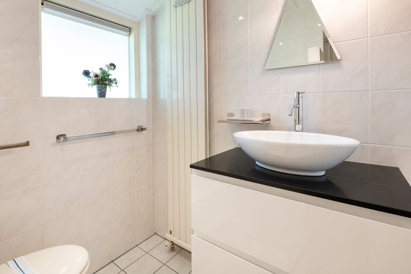 Een moderne badkamer met een stijlvolle wastafel en tegelvloer.