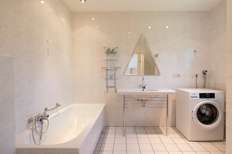 Een moderne badkamer met een spiegel, bad en wastafel.