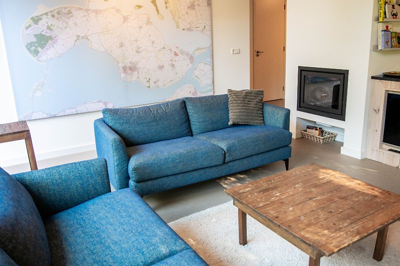 Gemütliches Wohnzimmer mit blauem Sofa, Holztisch und Kunst an der Wand.