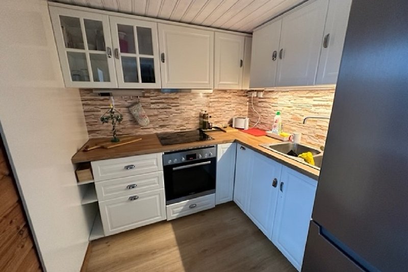 Eine moderne Küche mit Holzboden, Granit-Arbeitsplatte und Küchengeräten.