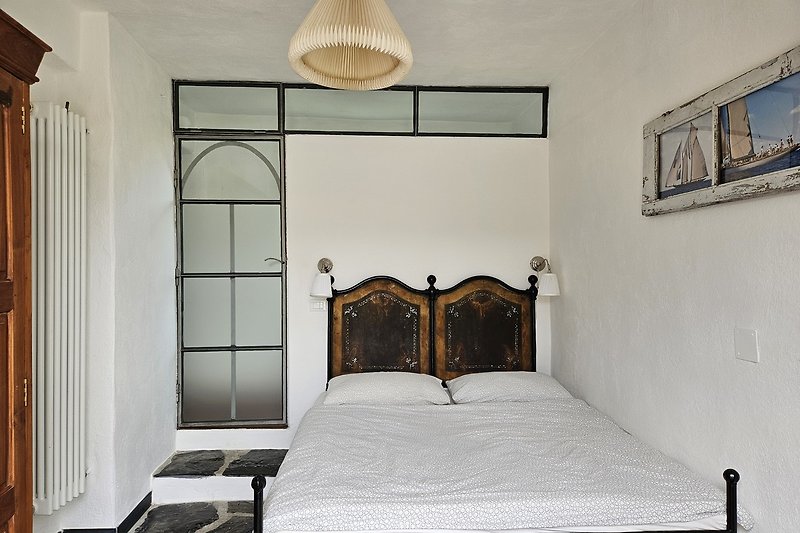 Schlafzimmer mit elegantem Bett, Holzmöbeln und stilvoller Beleuchtung.