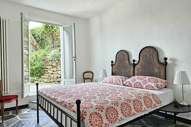 Schlafzimmer mit gemütlichem Bett, Holzmöbeln und Pflanzen.