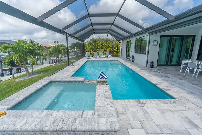 Luxuriöses Schwimmbad mit modernem Gebäude und tropischer Umgebung.