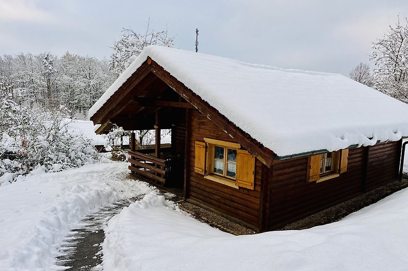 Ein winterliches Holzhaus mit Blick auf die verschneite Landschaft.