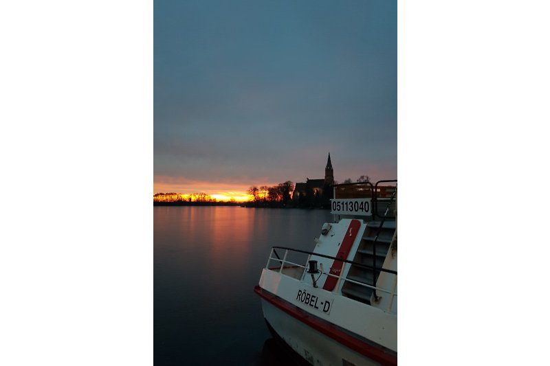 Boot auf ruhigem See bei Sonnenuntergang.
