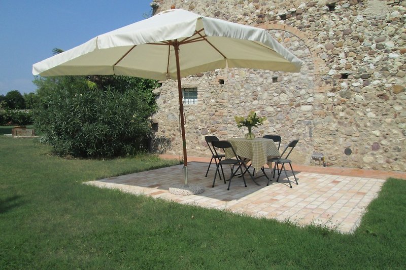 Terrasse mit Esstisch,  Stühlen und  Sonnenschirm.