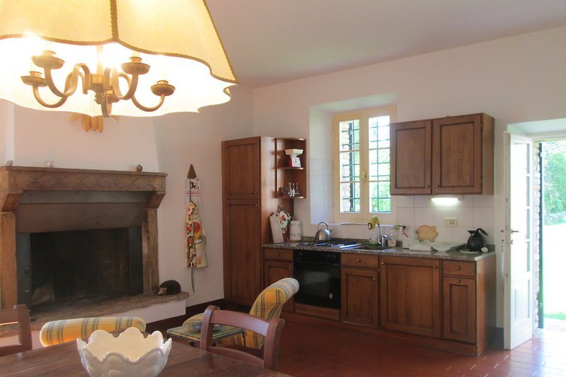 Cuisine-salle à manger avec lave-vaisselle et cheminée ouverte, la porte mène directement au jardin.