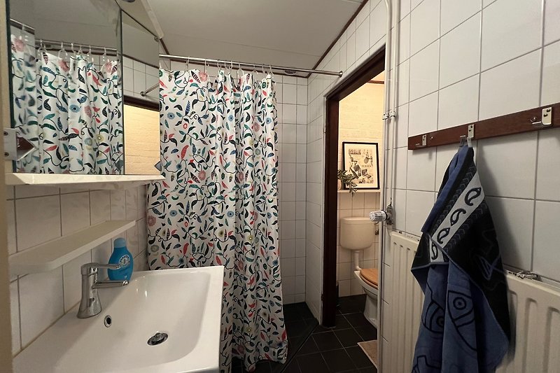Badezimmer mit Spiegel, Waschbecken und Dusche.