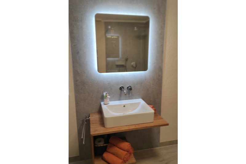 Modernes Badezimmer mit Keramikwaschbecken und Holzdetails.
