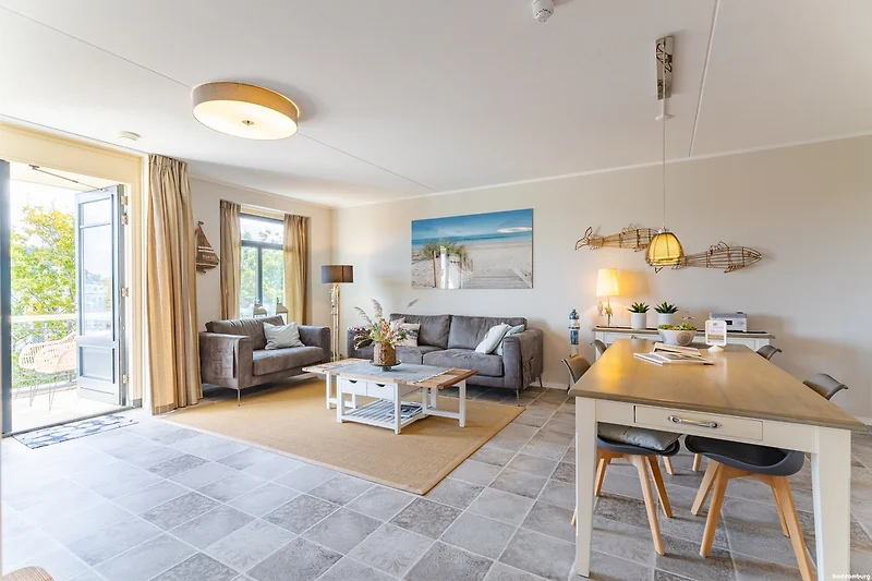 Wohnzimmer mit Couch, Sesseln und offener Küche.