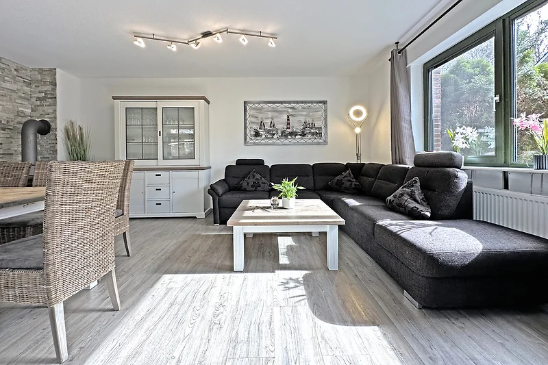 Großzügiger Wohnbereich mit Sofa, Esstisch, Fernseher und Pflanzen.