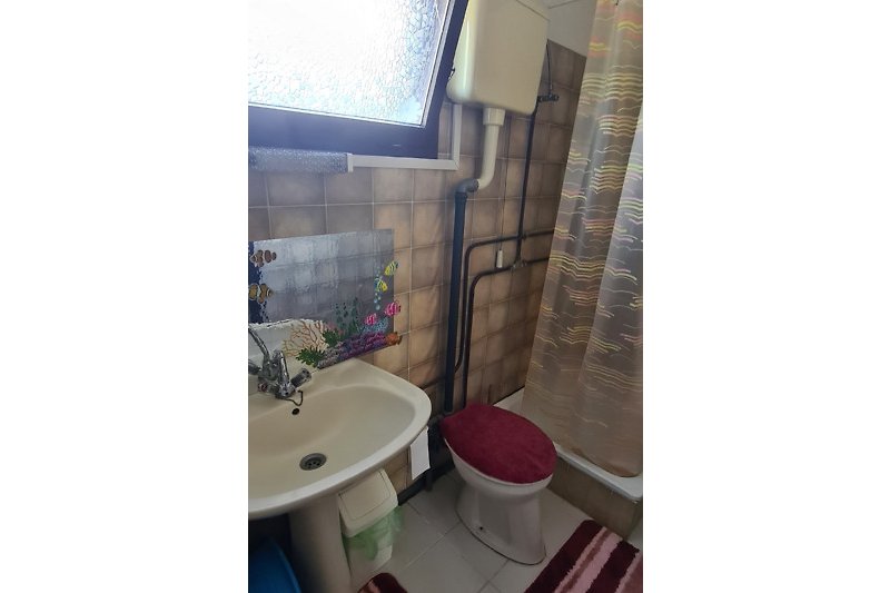 Schönes Badezimmer mit lila Vorhang und Keramikwaschbecken.