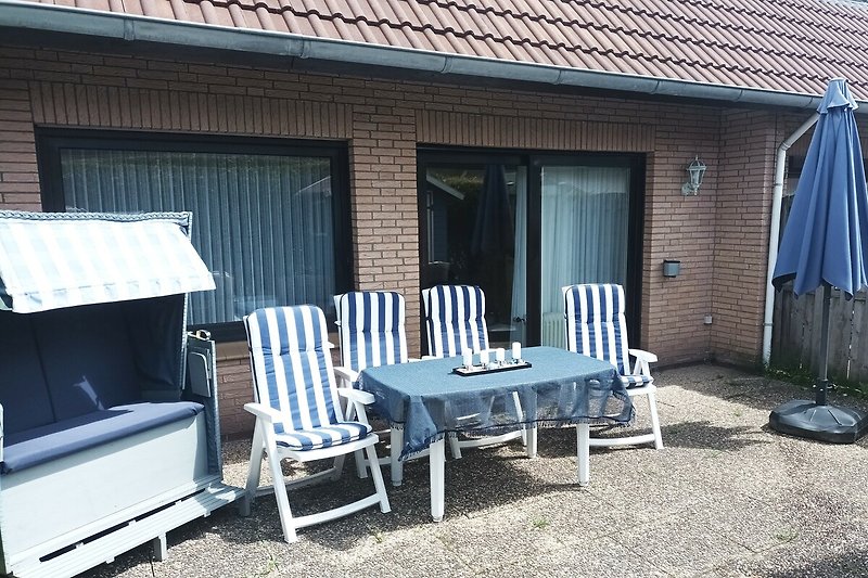 Terrasse Südseite mit Strandkorb, Tisch, Stühlen, 2 x Liegestühle, Sonnenschirm, Holzkohlegrill