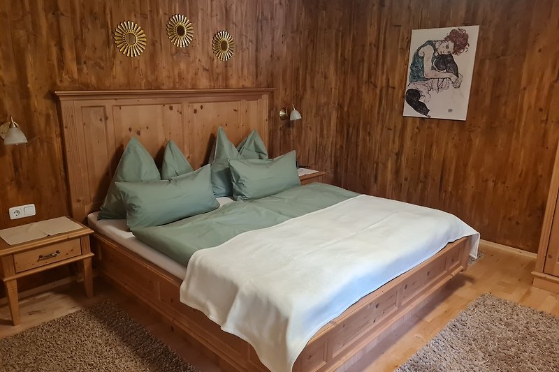Schlafzimmer mit Holzmöbeln und Bettwäsche. Gemütliche Atmosphäre.