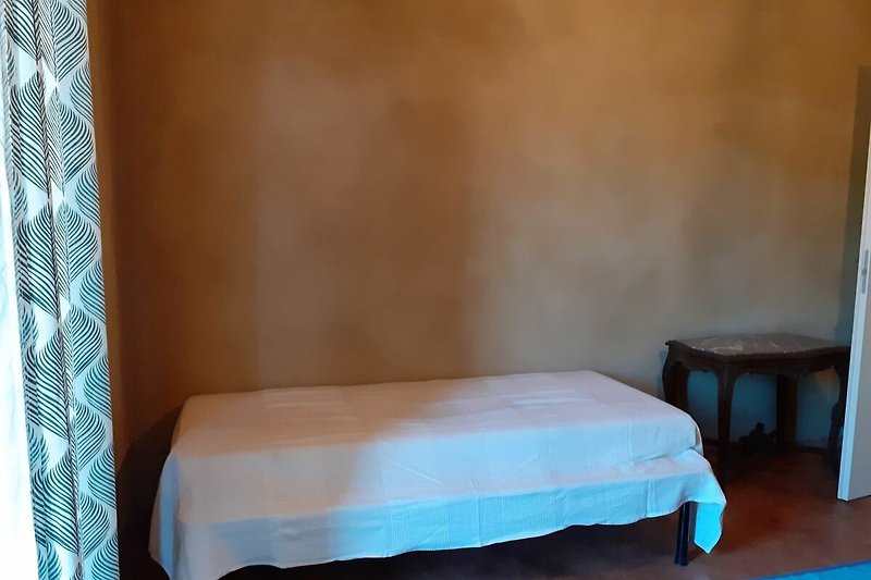 Schlafzimmer mit Holzmöbeln, Bettwäsche und blauer Decke.