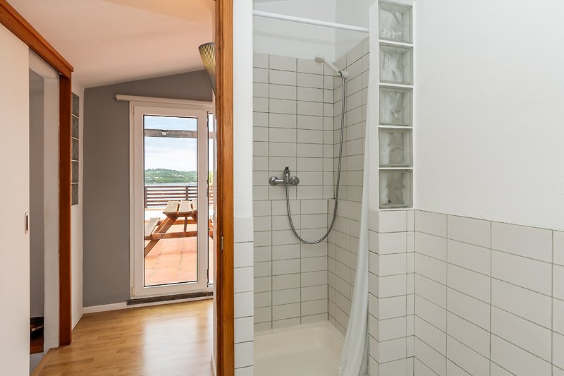 Modernes Badezimmer mit Glasdusche und Holzdetails.