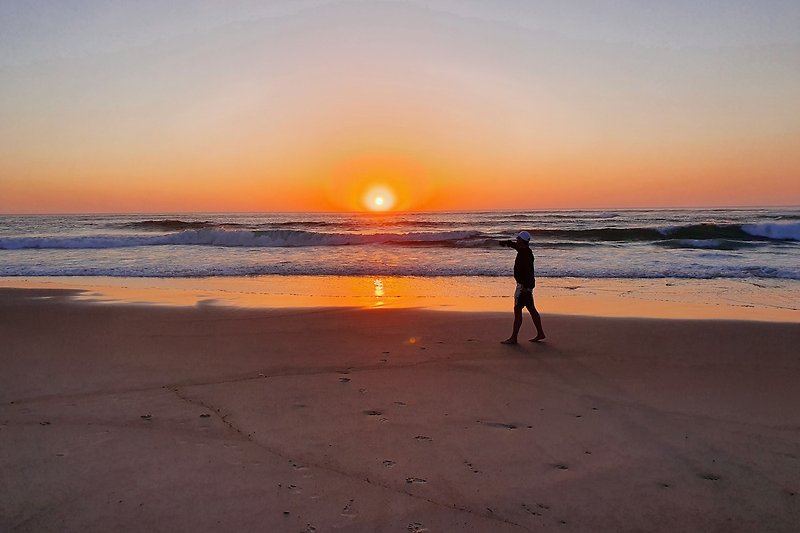 Strand mit Menschen, Sonnenuntergang über dem Ozean.