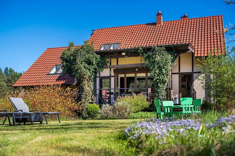 Grüner Garten mit Rasen, Bäumen und einem kleinen Landhaus.