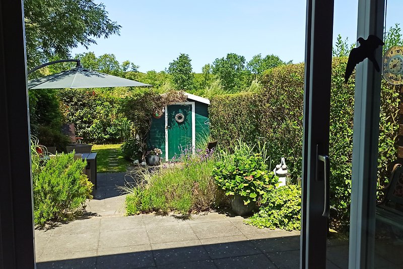 Blick aus dem Wohnzimmer auf Garten und Düne mit Übergang im Hintergrund - Sonnenschirm UV-Schutz 80+