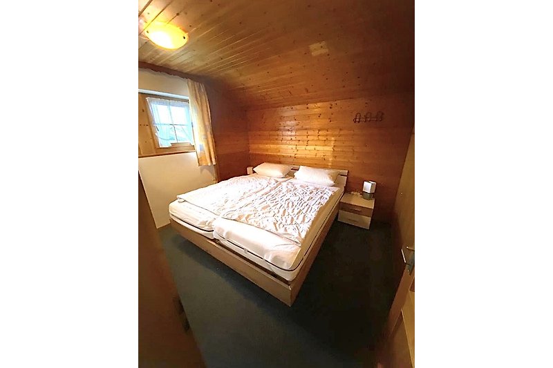Gemütliches Schlafzimmer mit Holzmöbeln und bequemem Bett. Genießen Sie den Komfort und die schöne Aussicht aus dem Fenster.
