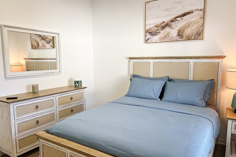 Schlafzimmer mit gemütlichem Bett, stilvollem Bilderrahmen und Holzmöbeln.