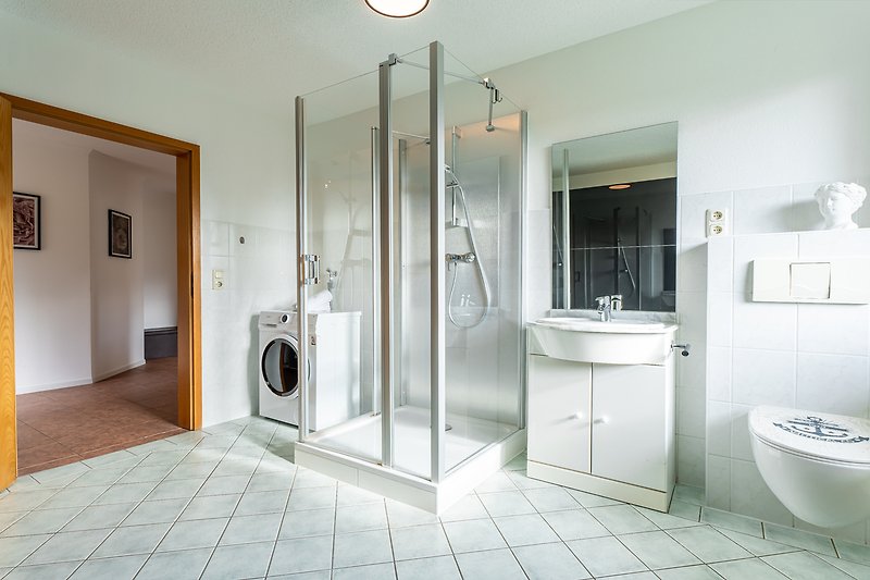 Modernes Badezimmer mit WC, Waschmaschine und Dusche.