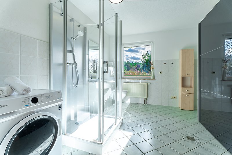 Modernes Badezimmer mit Dusche, WC, großer Kleiderschrank und Waschmaschine.