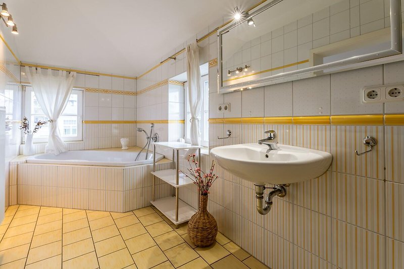 Modernes Badezimmer mit Spiegel, Badewanne und Waschbecken.