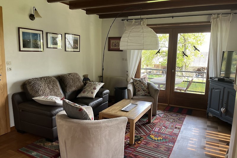 Wohnzimmer mit Holzmöbeln, gemütlicher Couch und Pflanzen.