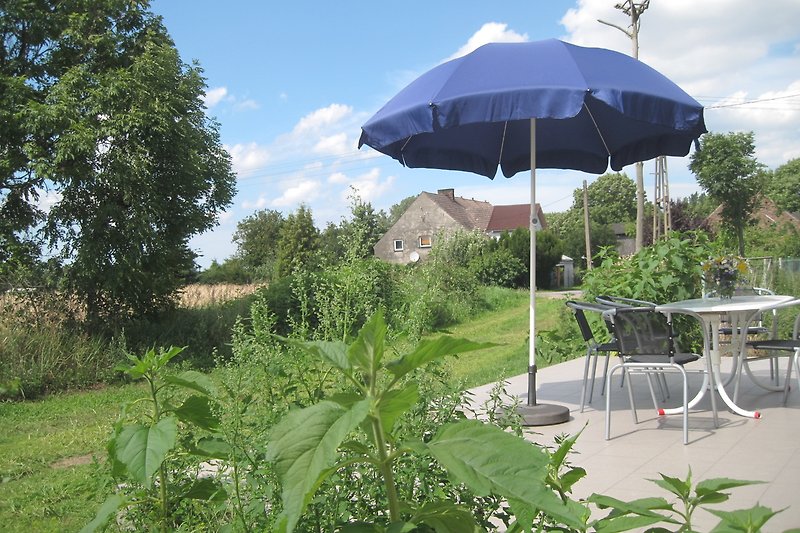 Tropische Gartenlandschaft mit Sonnenschirm und Outdoor-Möbeln.