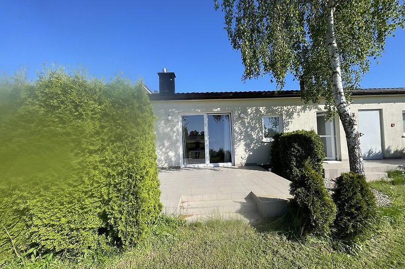 Ländliches Haus mit Garten, Bäumen und blauem Himmel.