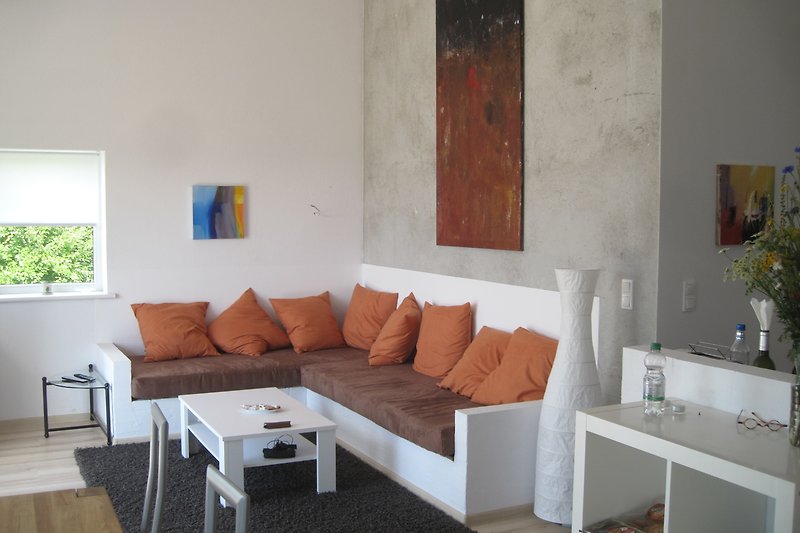 Modernes Wohnzimmer mit Holzmöbeln, orange Akzenten und Kunst. Gemütliche Sofaecke.