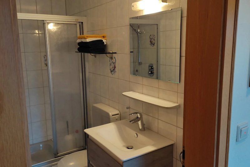 Modernes Badezimmer mit Spiegel, Waschbecken und Beleuchtung.