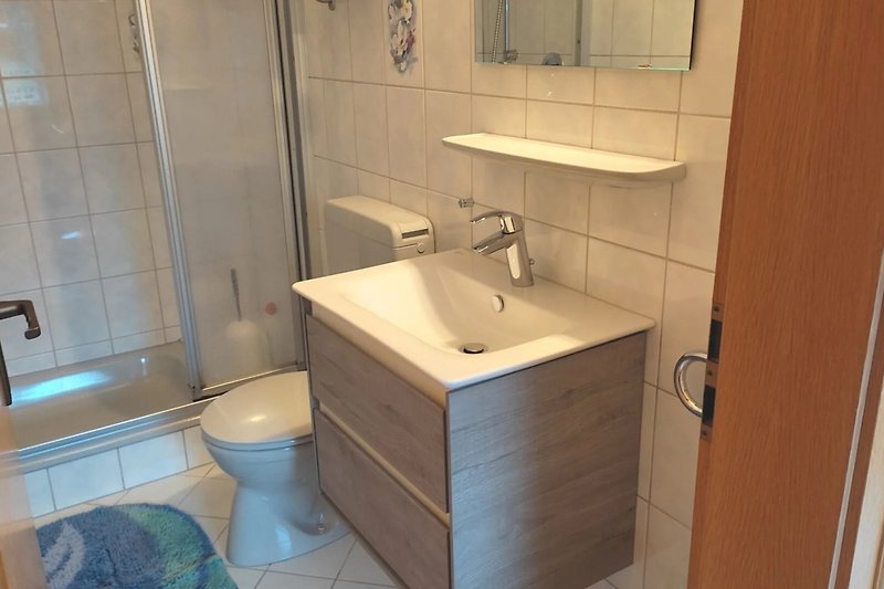 Badezimmer mit lila Akzenten, Spiegel, Waschbecken und Toilette.