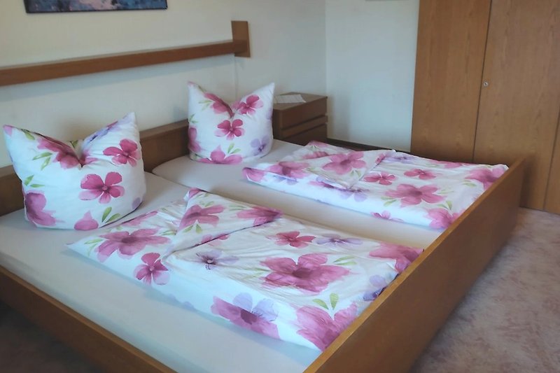 Gemütliches Schlafzimmer mit Holzmöbeln und lila Bettwäsche.